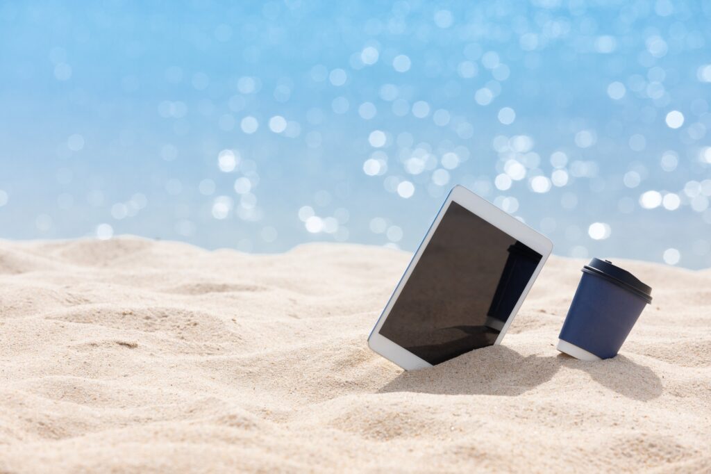 coffee paper cup with tablet put on the white sand beach - Summer relax and marketing digital.